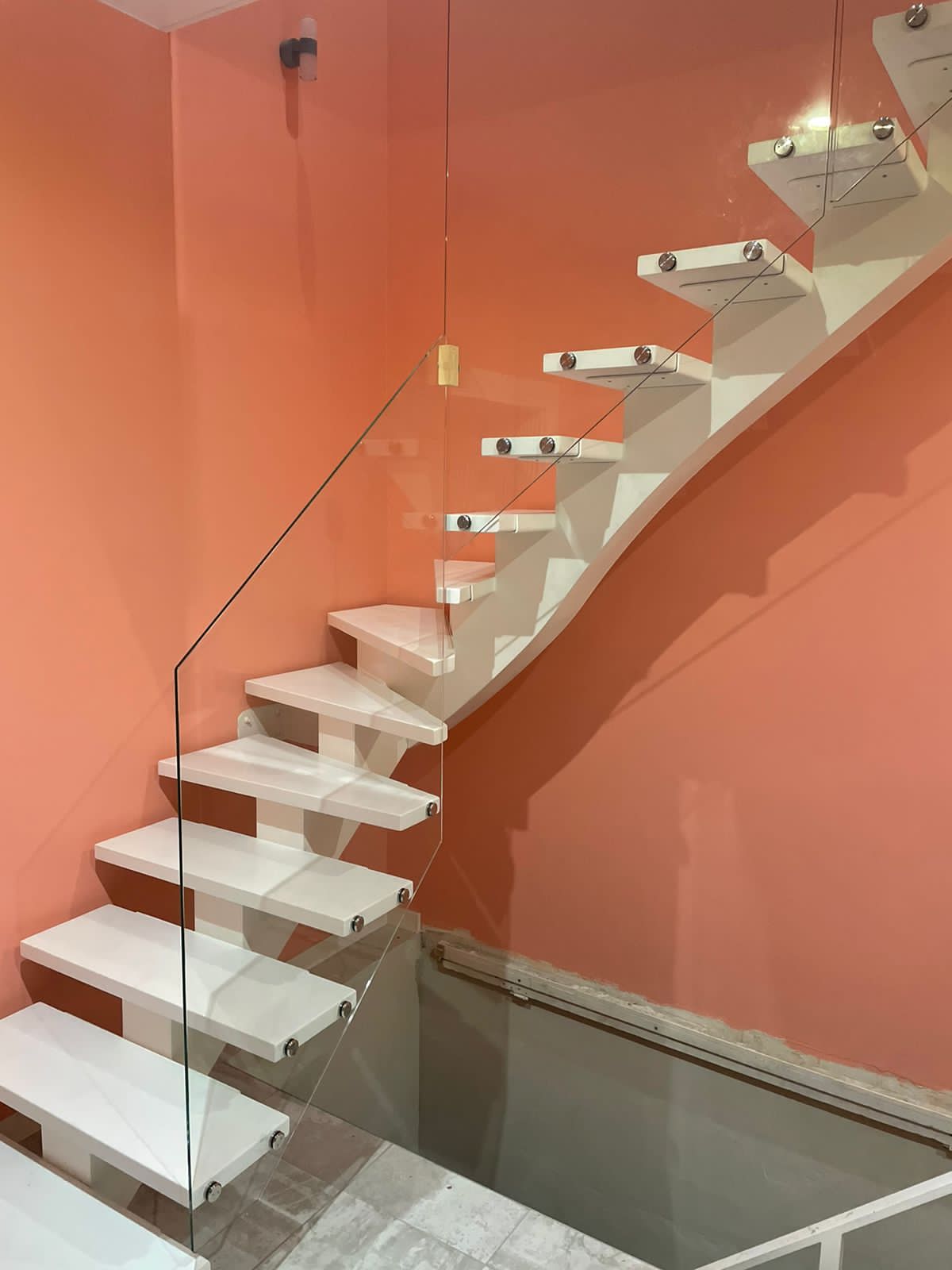 Поворотная лестница на белом монокосоуре со стеклянными перилами