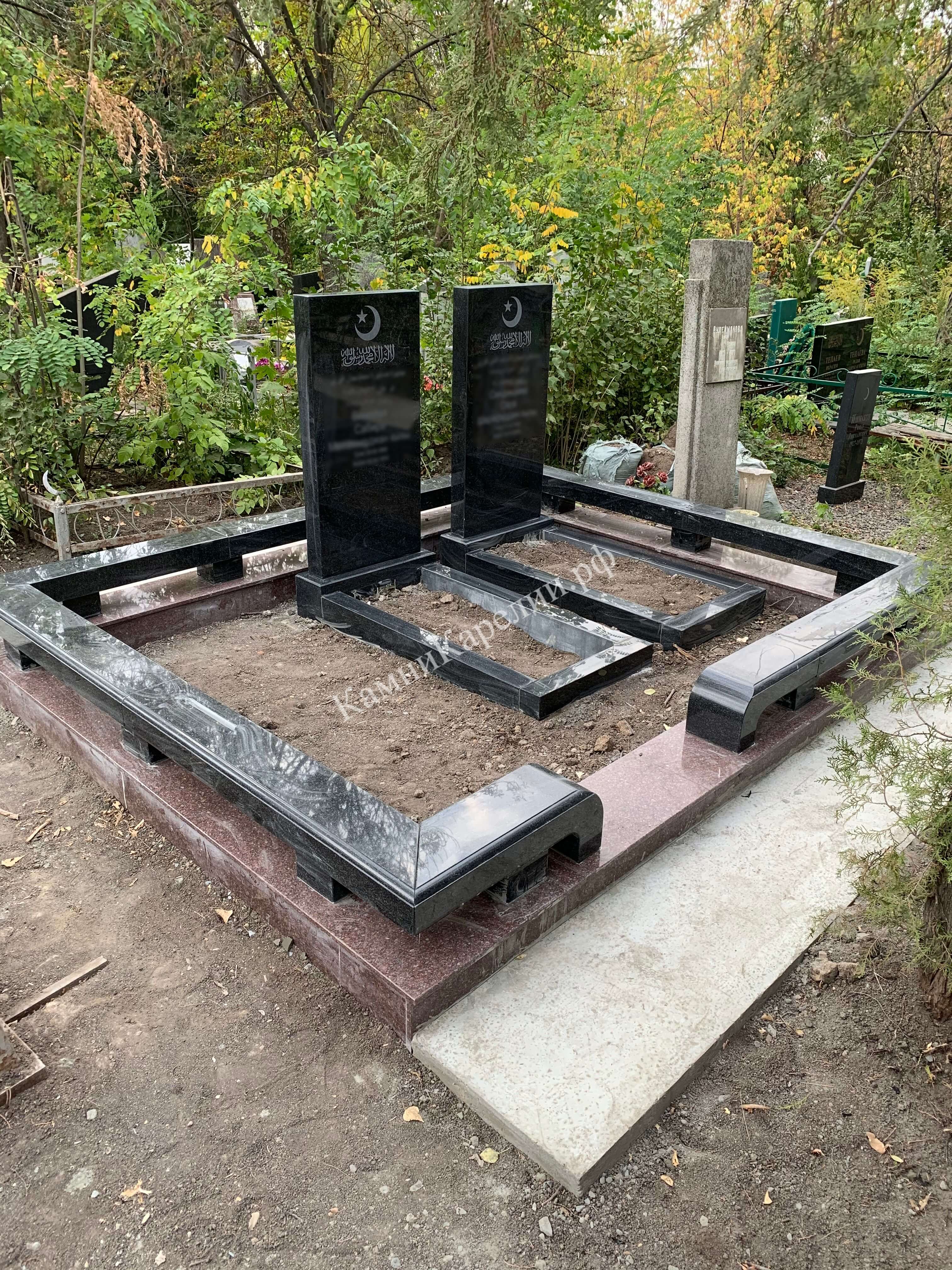 Комплекс гранитных памятников для двойного захоронения с надгробиями из чёрного карельского габбро-диабаза покрыт плитками темного мрамора с крупными разводами.