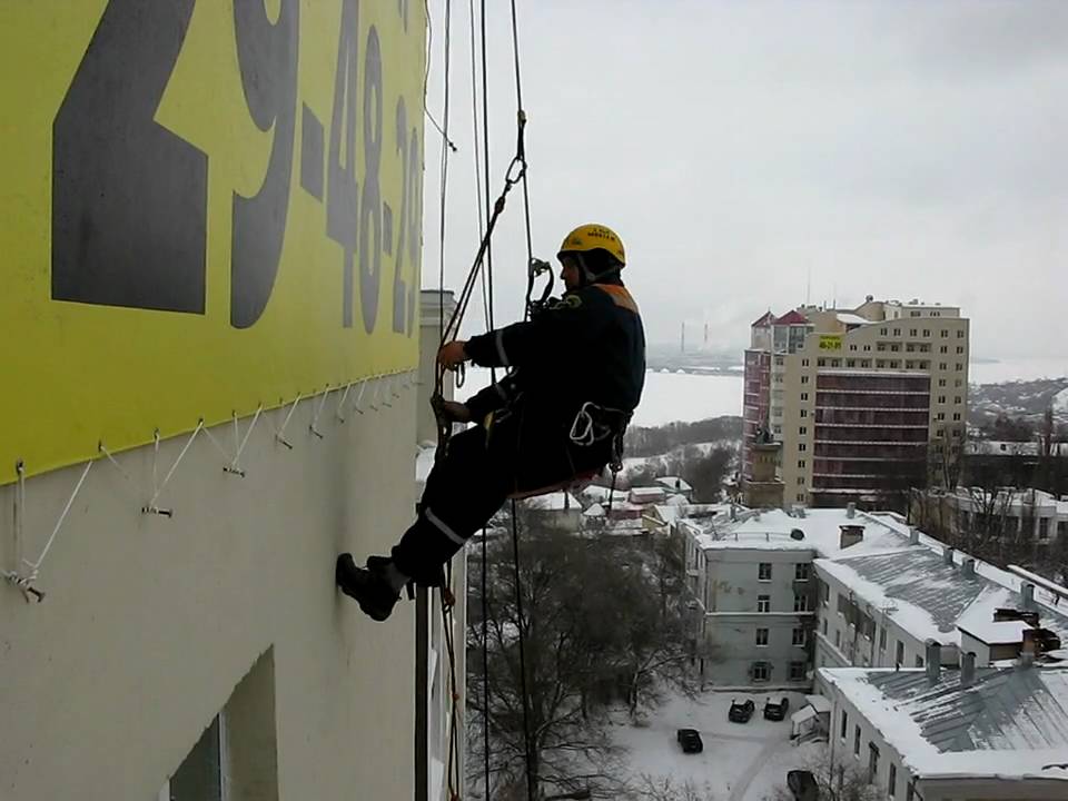 Норильск промышленный альпинист. Промышленный альпинизм. Монтаж баннера альпинистами. Промышленный альпинист. Монтаж рекламных баннеров.