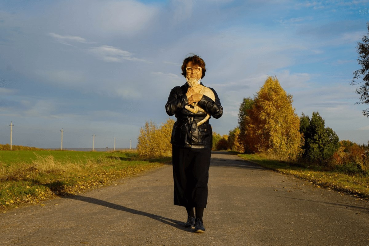 Заводчица Ирина Курсакова идёт по дороге с девон-рексом на руках